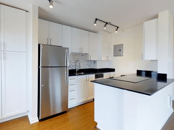 A kitchen with white cabinets and a black countertop at Skye at Belltown Apartments, Seattle, WA 98121
